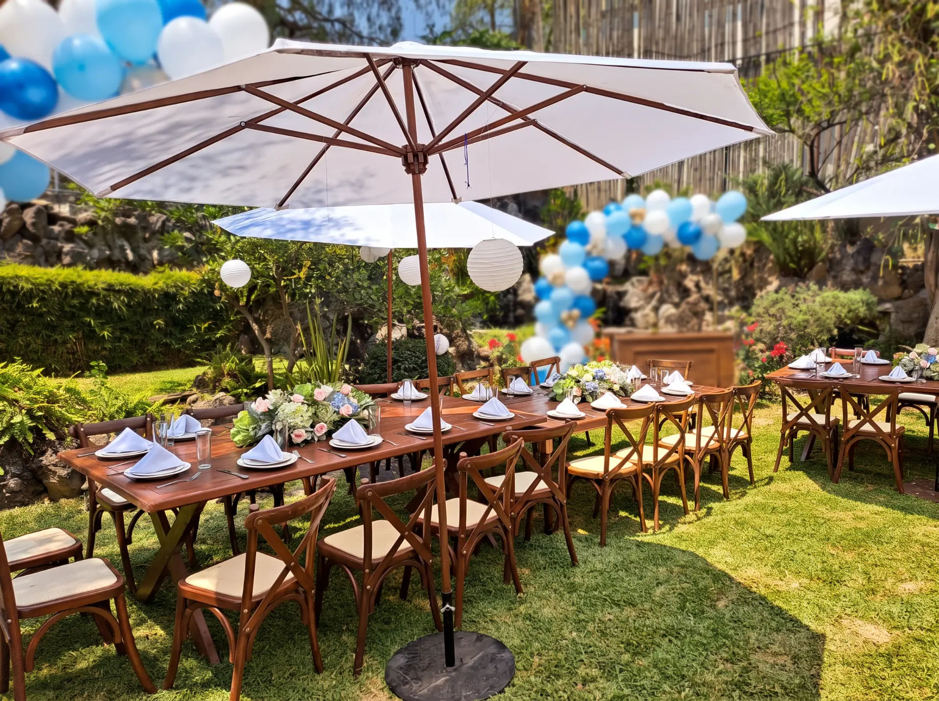 Mesas de madera en jardín con globos azules